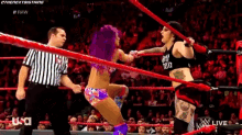 two women are wrestling in a ring with a referee in the background .
