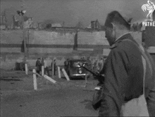 a black and white photo of a man standing next to a man on a motorcycle