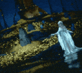 a woman in a long white dress is standing in a body of water