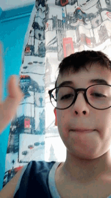 a boy wearing glasses is laying on a bed in front of a curtain that has a picture of a ski resort on it