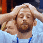 a man with a beard is holding his head with his eyes closed
