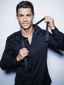 a man in a black shirt is tying a black tie