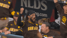a san diego padres baseball player is sitting in the dugout with his hands in the air