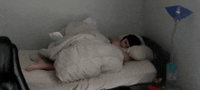 a person laying on a bed with a white blanket and pillows