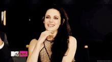 a woman is smiling in front of a mtv news banner .