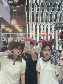 three girls are taking a selfie in front of a sign that says ' nxkpb '