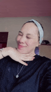a woman wearing a headband and a necklace smiles