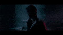 a man is standing in a dark room with red lights and chains