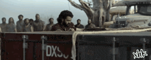 a group of men are standing around a container that says dxs on it