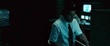 a group of men are sitting at a desk in front of a computer monitor in a dark room .
