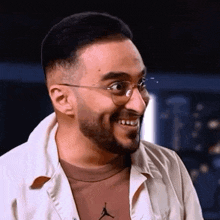 a man with glasses and a beard is smiling and making a funny face .