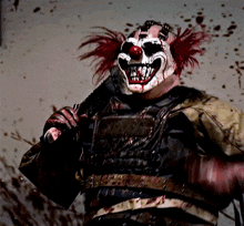 a clown with blood on his face is holding a knife