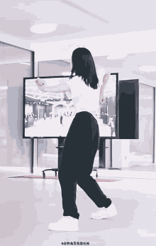 a woman in a white shirt and black pants is dancing