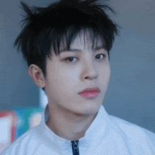 a close up of a boy 's face with a white jacket on