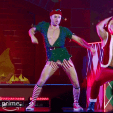 a man in a green shirt and red hat is dancing in front of a sign that says prime on it