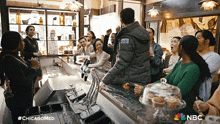 a group of people are gathered at a bar with a nbc logo on the bottom