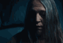 a woman with long blonde hair is looking at the camera with a serious look on her face