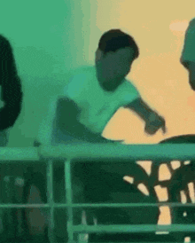 a man in a white shirt is sitting at a table with a green background .
