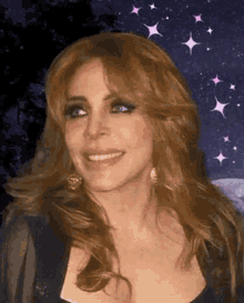 a woman with long brown hair and blue eyes is smiling in front of a night sky with stars .