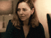 a woman in a black shirt and earrings looks at the camera