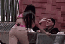 a woman is standing next to a man sitting on a couch while a man looks on .