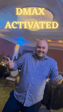 a man is giving a thumbs up in front of a sign that says " dmax activated "