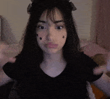 a girl with stars on her face is making a heart with her hands .