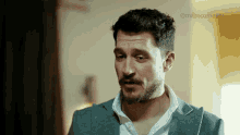 a man with a beard is wearing a blue suit