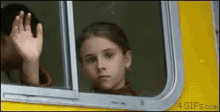 a girl is waving from the window of a yellow bus .