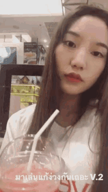 a woman with long hair is drinking from a plastic cup with a straw in front of a sign that says square day