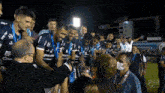 a group of soccer players are celebrating a victory with a man in a mask