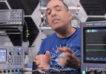 a man wearing a blue shirt that says pull brand is standing in front of a keysight monitor