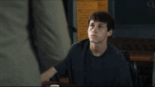 a young man in a black t-shirt is looking at something
