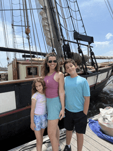 a woman and two children are standing in front of a boat