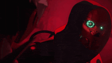 a red robot with green eyes and a hood