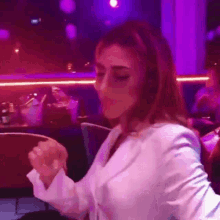 a woman in a white jacket is dancing in a purple room