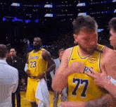 a basketball player with the number 77 on his jersey is standing next to a basketball player with the number 23 on his jersey .