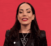 a woman wearing a black leather jacket and a necklace with a triangle on it