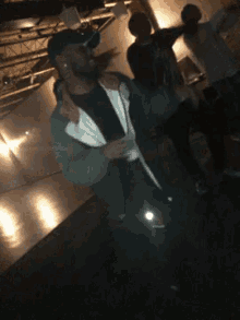 a group of people are dancing in a dark room and one of them is wearing a hat