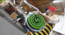 a man in a striped shirt is holding a green mother frisbee
