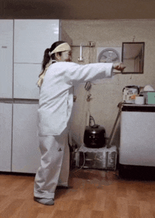 a woman in a white adidas outfit is standing in front of a refrigerator