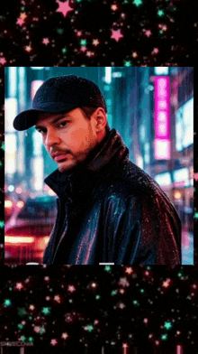 a man wearing a black hat and a leather jacket is standing in front of a city street at night