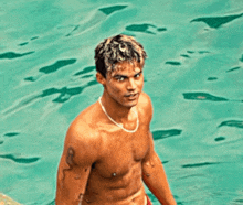 a shirtless man with a tattoo on his arm is standing in a pool
