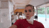 a woman wearing a mask and a red shirt is taking a selfie .