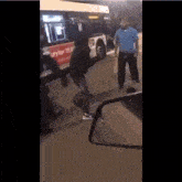 a man in a blue shirt is standing next to a woman in a black hoodie in front of a bus .