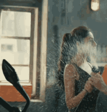 a woman is spraying water on her face while using a cell phone