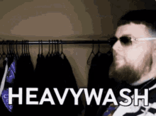 a man wearing sunglasses is standing in front of a rack of clothes with the words heavywash written on it