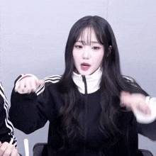a girl with long black hair is wearing a black jacket