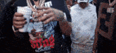 a man wearing a shirt that says song later is holding a cup