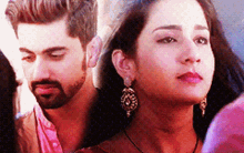 a man and a woman are standing next to each other . the woman is wearing earrings .